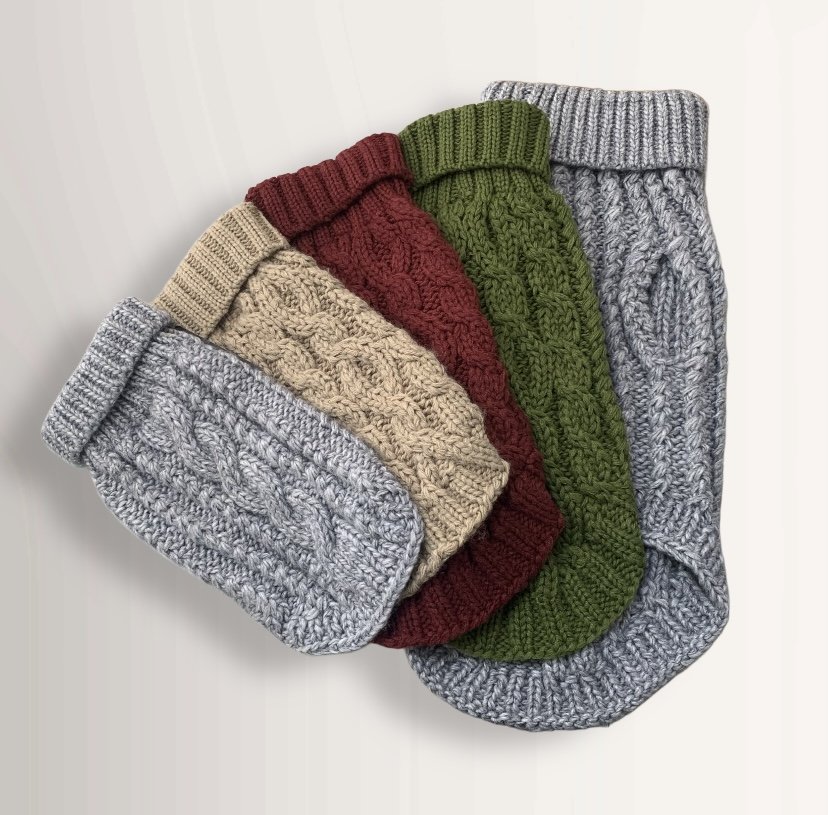 Four hand-knitted cable dog jumpers in cream, burgundy, olive and grey